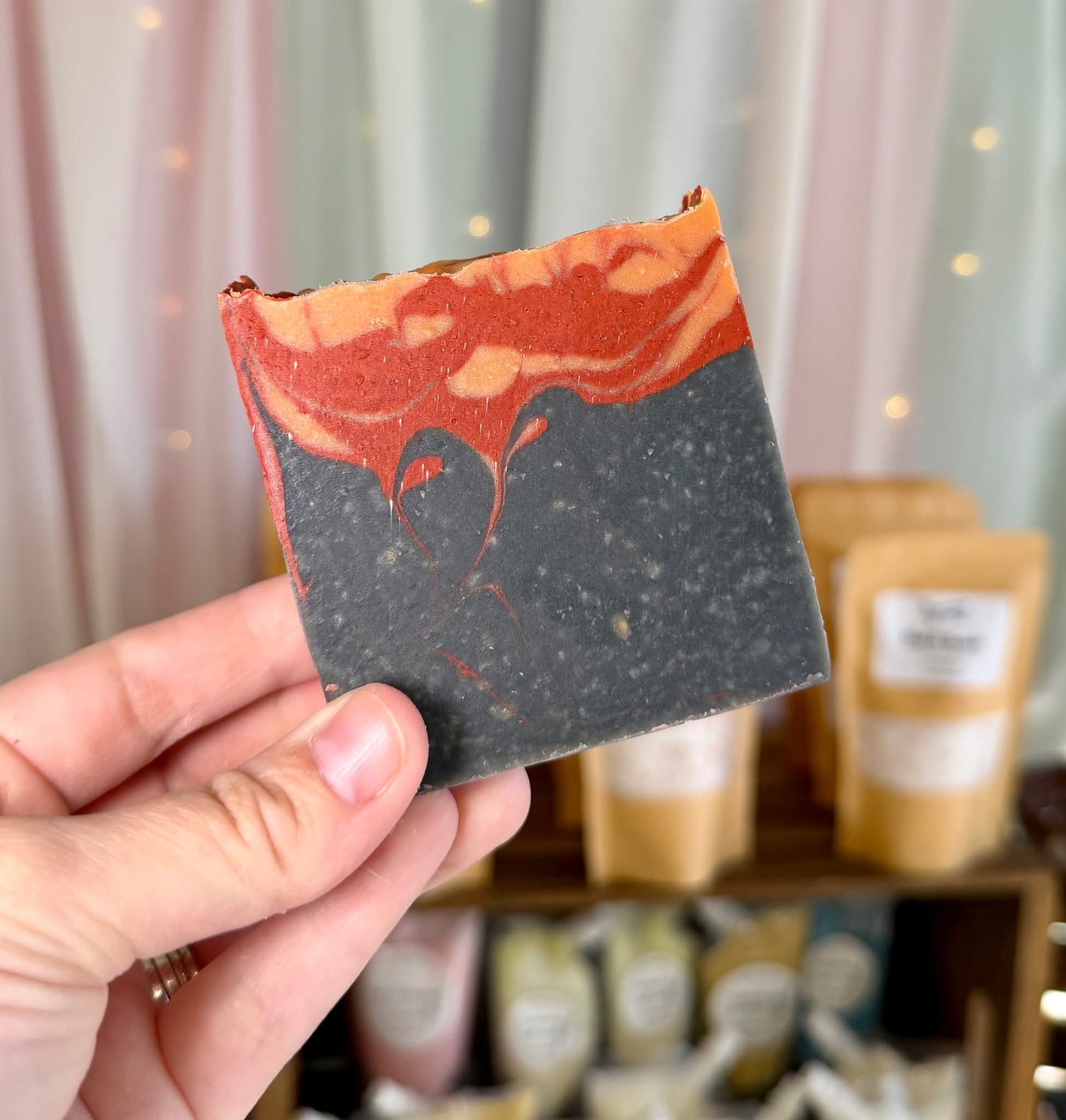 A bar of soap with a black charcoal bottom half resembling smoke, topped with red and orange swirls resembling flames.