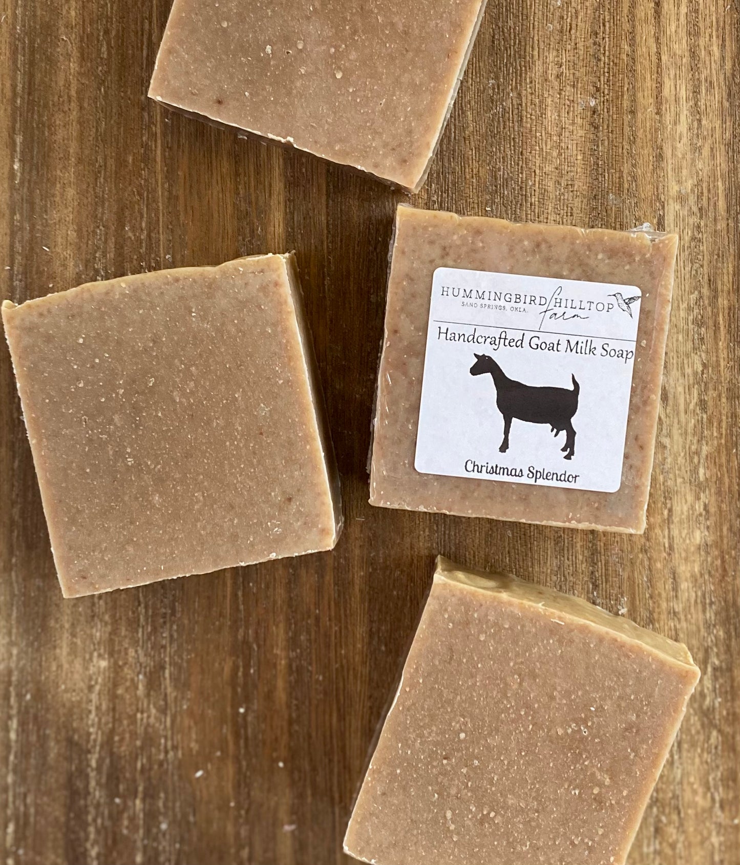 4 bars of brown soap on a wooden surface. One bar is shrinkwrapped and labeled.