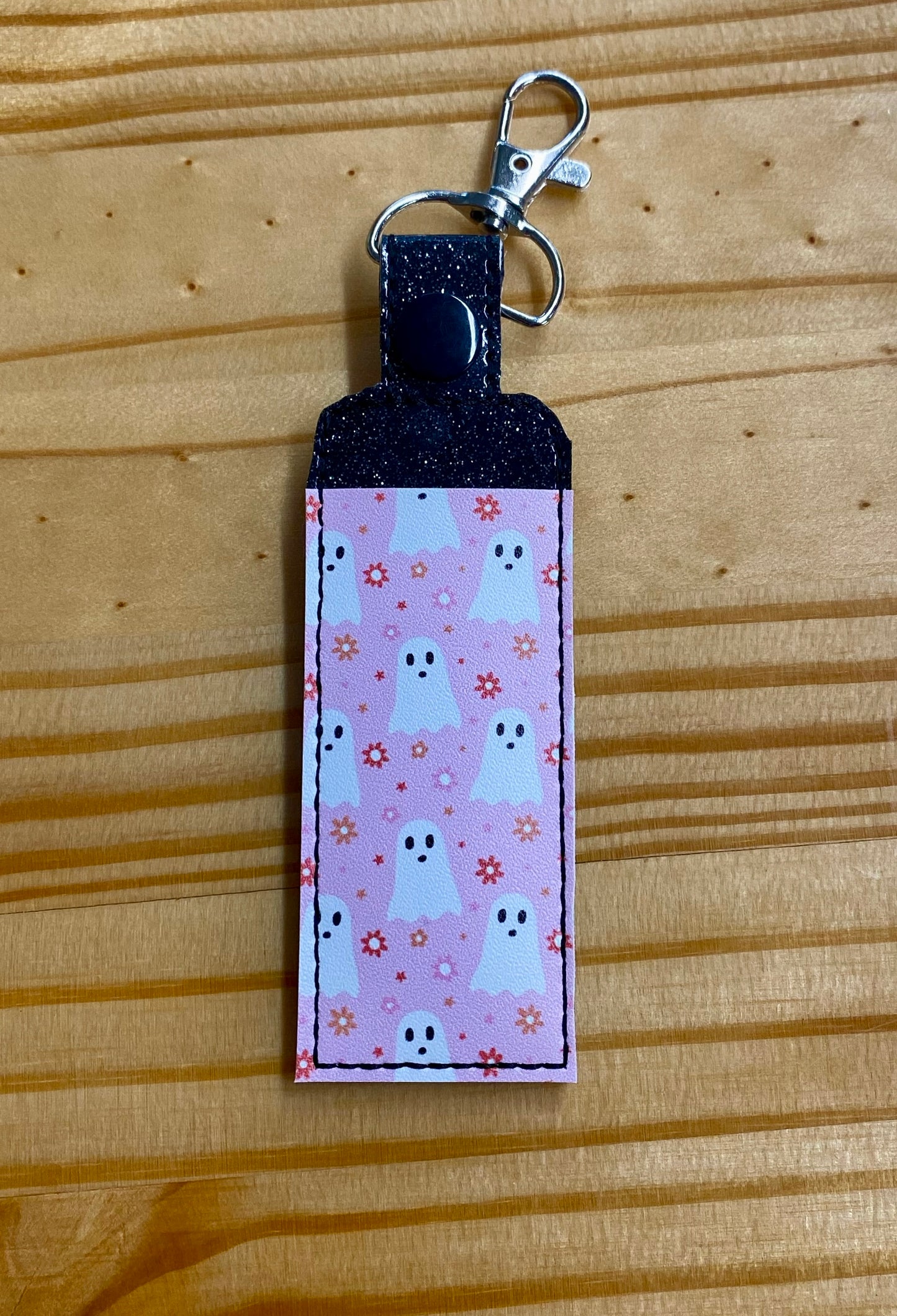 Lipbalm holder with pink ghost pattern on a wooden surface
