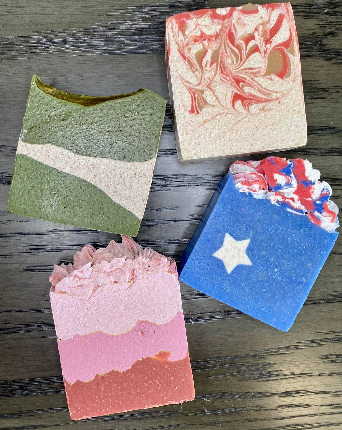 Four soap bars with different designs on a wooden surface