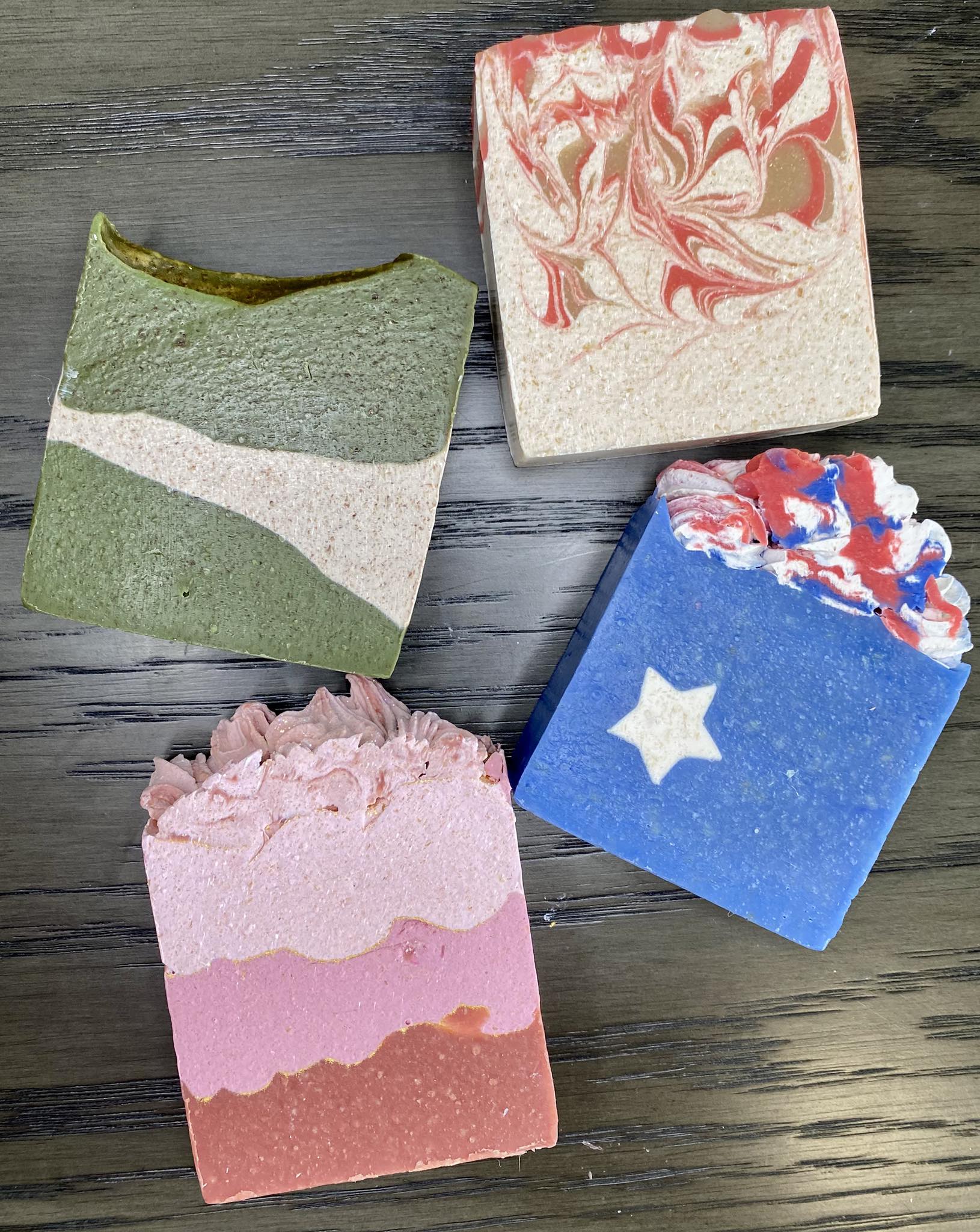 Four soap bars with different designs on a wooden surface